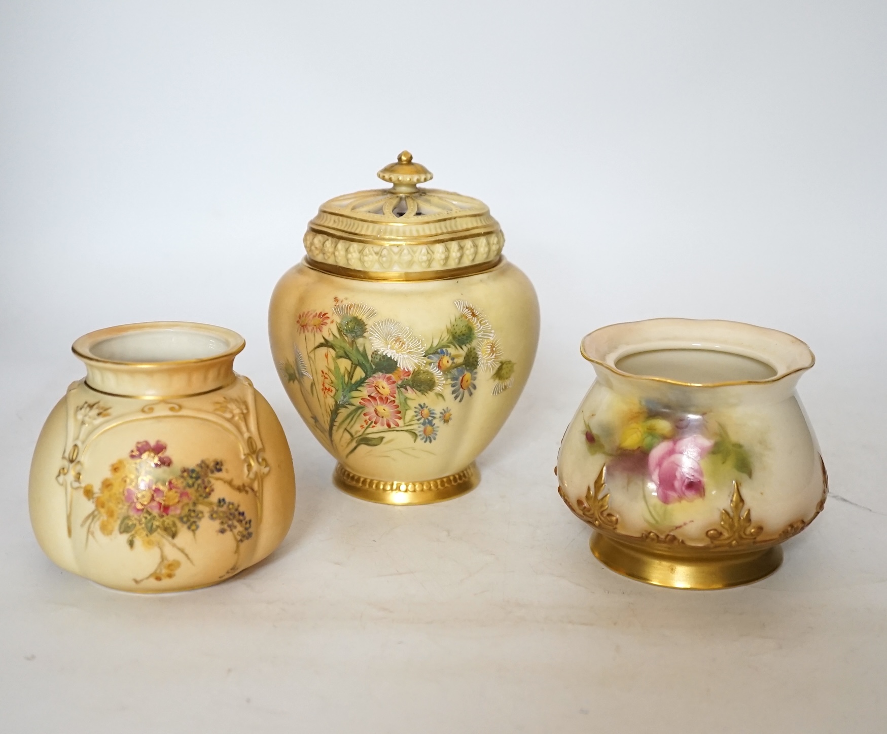 Three Royal Worcester blush ivory pots, one with an inner lid and pierced outer lid, tallest 14cm